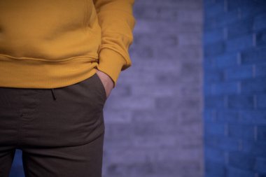 Metnin için kopyalanmış tuğla bir duvara karşı genç bir kadının vücudunun ön yüzü. Tanınmayan bir kadının elini pantolonunun cebine koy.