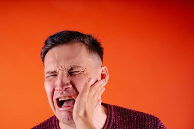 Turuncu arka planda tokat yiyen bir adam. Turuncu arka planda duran mutsuz, korkmuş bir adam.