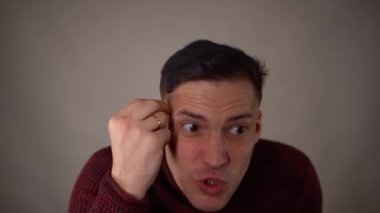 Ürkek bir adamın suratına tokat atıyor. Duygusal erkek, beyaz arka planda gözleri kapalı bağırırken tokat yiyor.