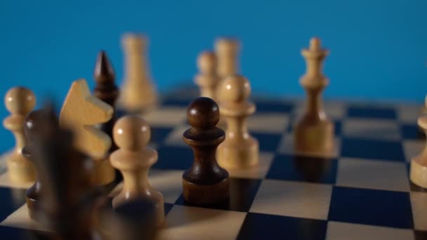 棋盘上的白色和黑色木制棋子 棋盘在蓝色背景的比赛中设置的棋盘 — 图库视频影像