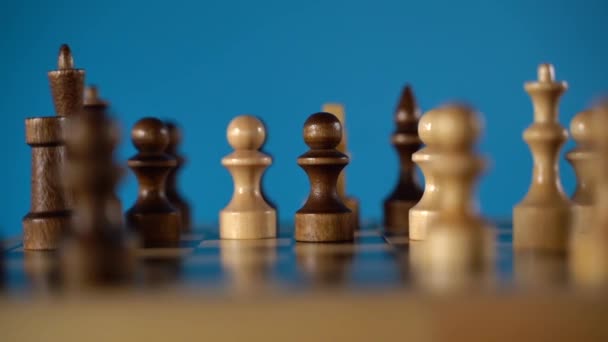 Primer plano del ajedrez sobre un fondo azul. Piezas de ajedrez de madera. Concepto: el juego de mesa y las actividades intelectuales — Vídeos de Stock