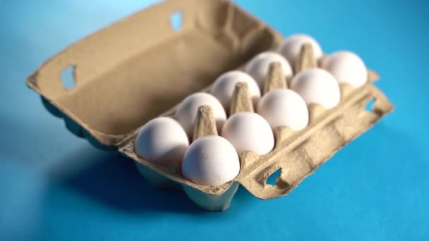 Granja huevos de gallina crudos y frescos en una caja de huevos sobre un fondo azul. Huevos en cartón. Huevos en la canasta. Concepto: un huevo fresco para el desayuno de la mañana. — Vídeo de stock