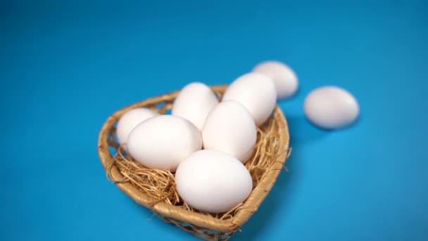 Gård rå, färsk vit kyckling ägg i en korg på en blå bakgrund. Koncept: ett färskt ägg till morgonfrukosten. — Stockvideo