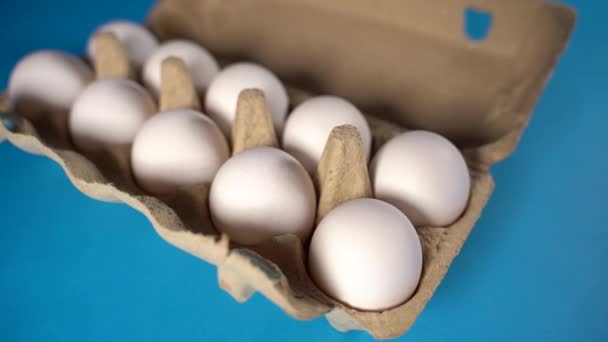 Fazenda cru, ovo de galinha branco fresco em uma caixa de ovo em um fundo azul. Ovos na caixa. Ovos no cesto. Conceito: um ovo fresco para o café da manhã. — Vídeo de Stock