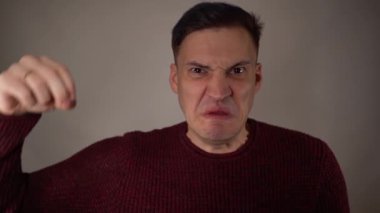 Beyaz arka planda kızgın bir adamın portresi. Saldırgan adam kameraya bakarak bağırıyor..