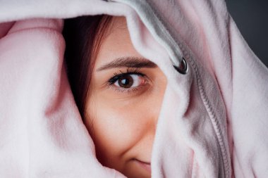 Kapüşonlu genç bir kadının portresi. Sweatshirt 'ün içinde saklanan ve gizlice gözetleyen güzel bir kadın.