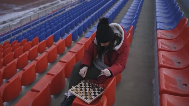 Jovem Mulher Roupas Inverno Joga Xadrez Sentado Bancadas Estádio Sozinho — Vídeo de Stock