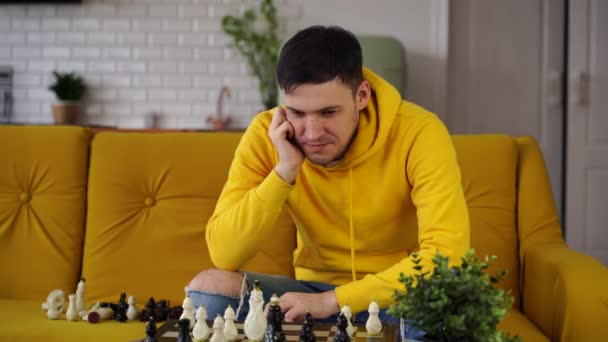 Junger Mann Sitzt Auf Gelbem Sofa Und Spielt Schach Zimmer — Stockvideo