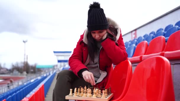 Jonge Vrouw Winterkleding Schaakt Zit Alleen Stadiontribune Vrouw Met Zwarte — Stockvideo