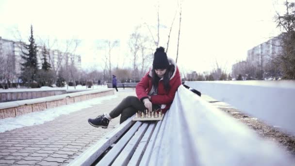 Młoda Kobieta Zimowych Ciuchach Gra Szachy Siedzi Ławce Parku Miejskim — Wideo stockowe