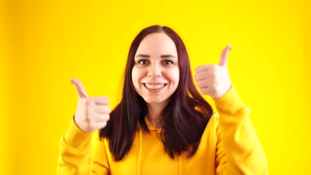 Портрет Молодої Жінки Яка Посміхається Показує Великі Пальці Жовтому Тлі — стокове відео