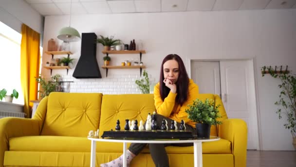 Jovem Mulher Sentada Sofá Amarelo Jogando Xadrez Quarto Feminino Jogando — Vídeo de Stock