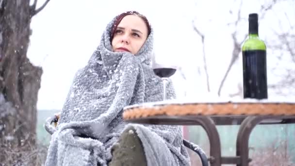 年轻女子坐在院子里 在雪天喝红酒 裹着灰色格子花的女人们坐在街上喝酒 — 图库视频影像
