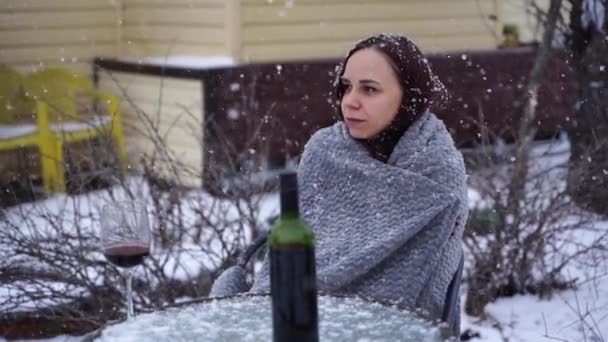 年轻女人摆姿势 坐在院子里的街上 冬季野餐时 女性裹着灰格子花和酒精 — 图库视频影像