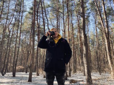 Ormandaki eski fotoğraf makinesinde fotoğraf çeken genç bir adam. Baharın başında eski fotoğraf makinesiyle fotoğraf çeken yakışıklı bir adam.