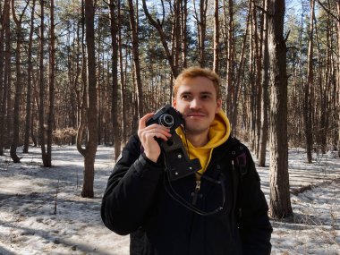 Ormandaki eski fotoğraf makinesinde fotoğraf çeken genç bir adam. Baharın başında eski fotoğraf makinesiyle fotoğraf çeken yakışıklı bir adam.