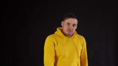 Genç adam siyah arka planda yanaklarını tokatlıyor. Duygusal adam ellerini kontrol edemiyor ve suratına tokat yiyor..