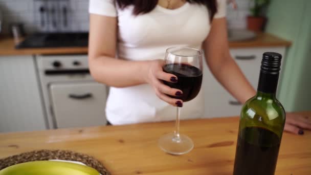 Close up de mulher irreconhecível sacode bem o copo de vinho tinto na cozinha. Desconhecido feminino treme copo de vinho com álcool. Movimento lento. — Vídeo de Stock