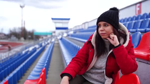 Jonge Vrouw Winterkleding Kijkt Weg Zittend Stadiontribune Alleen Vrouw Met — Stockvideo