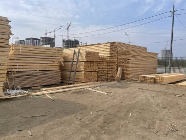 Mavi gökyüzünün arka planındaki tahta tahtaları kapatın. İnşaat alanında endüstriyel doğal kereste üretim malzemeleri