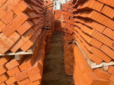 Şehir caddesinde kırmızı tuğlalı palet yığını. İnşaat alanındaki inşaat malzemeleri. Binalar inşa etme kavramı