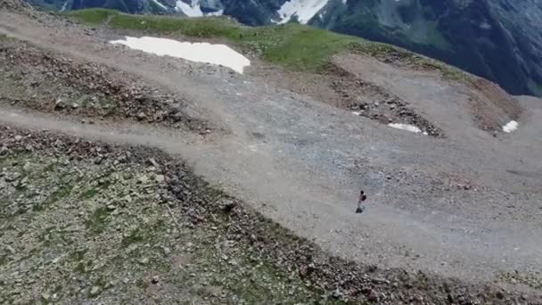 从空中俯瞰年轻女子在高原上行走的景象 阳光下背着背包去山区旅游的女性游客的鸟瞰图 — 图库视频影像