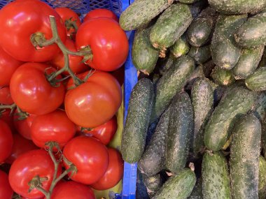 Domatesleri ve salatalıkları süpermarket tezgahındaki plastik kutulara koy. Tarım, organik gıda, sağlıklı beslenme ve diyet kavramı