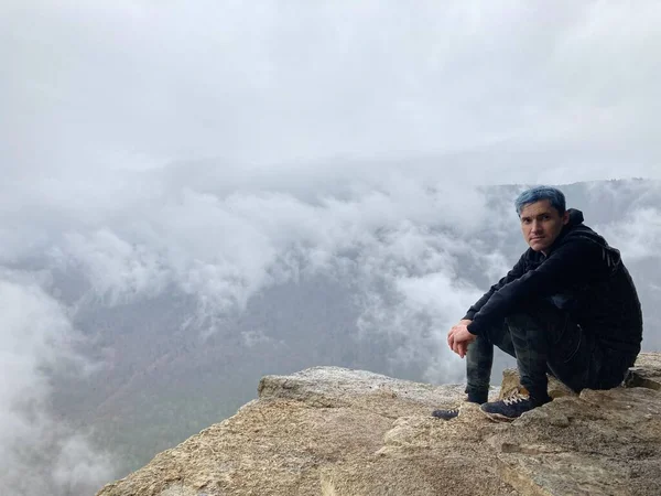 Young Man Blue Hair Sitting Edge Cliff Foggy Cloudy Weather — Stock Photo, Image