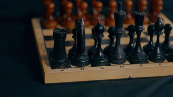 チェスボード上の木製の黒いチェスの駒を閉じます 未知の女性の手作る最初移動のホワイトポーン上のぼやけた背景 — ストック動画