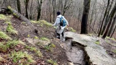Kayalık araziye dikkatle inen turistlerin arka görüntüsü. Yürüyüşteki engelleri aşan bir grup insan.