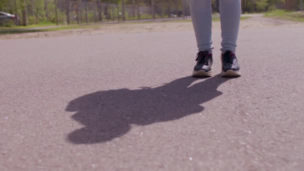 Női lábak közelsége az utcán napsütésben. Felismerhetetlen személy áll az aszfaltozott úton. — Stock videók