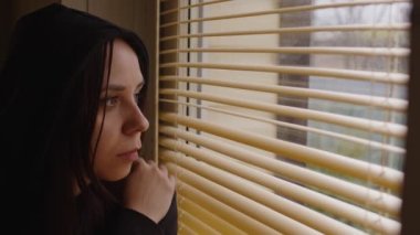 Pencere perdelerinden bakan genç bir kadına yaklaş. Meraklı kadın şaşkınlıkla ağzını açıyor, odanın penceresinden jaluziyi inceliyor.