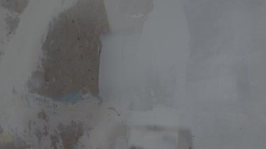 Odanın duvarına macun yapıştıran tanınmayan kişiye yakın çekim. Dairesinde spatulayla duvarları sıvayan kimliği belirsiz bir kadın. Tamir işleri ve konut koşullarının iyileştirilmesi.