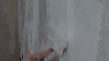 Bir kadın evinde tamirat yaparken duvara macun yapıştırıyor. Çalışma süreci, kadın işçi macun çözeltisi koyuyor. Kendi ellerinle onar..