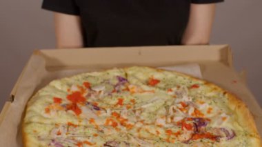 Tanınmayan kişilere yakın bir yerde içinde farklı malzemeler olan büyük pizza kutusu var. Apartmanında iştah açıcı yemekleri olan kimliği belirsiz bir kadın..