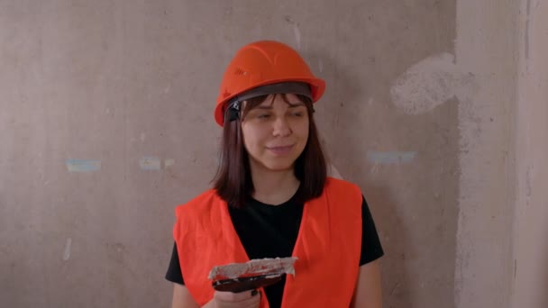 一个穿着工作服的年轻女人笑着把大拇指伸出来 建筑工地上的女建筑工人 带有水沫和油灰 — 图库视频影像