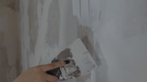部屋の壁にパテを適用する認識できない人の閉鎖 知られざる女性のアパートでへらで壁を漆喰 補修工事の概念及び住宅条件の改善 — ストック動画