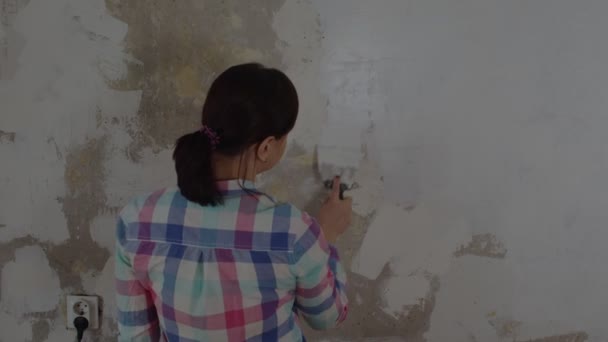 无法辨认的人在房间墙壁上涂油灰的后视镜 不认识的女人在公寓里贴满了水沫的墙 维修工作的概念和改善住房条件 — 图库视频影像