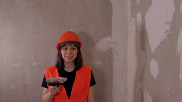 穿着工作服的年轻女子笑着走近镜头 建筑工地上的女建筑工人 带有水沫和油灰 — 图库视频影像
