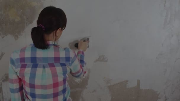 家の中で修理をしながら壁にパテをかける女性 仕事のプロセス 女性労働者はパテソリューションを置きます 自分の手で修理する — ストック動画