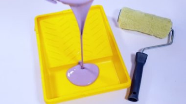 Plastik tepsiye dökülen mor boyayı kapat. Dairenin duvarlarını boyamak için sıvı malzeme hazırladım. Tamir işleri ve konut koşullarının iyileştirilmesi kavramı. Yavaş çekim.