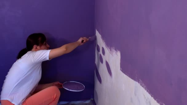 筆で紫の色で若い女性の絵画の壁の閉じる 壁にペイントを施した女性デザイナー 補修工事の概念及び住宅条件の改善 — ストック動画