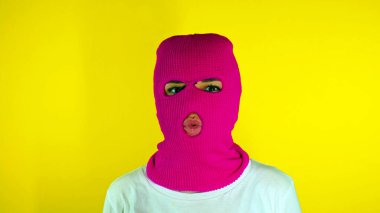 Pembe kar maskeli tanınmayan bir kadın sarı arka planda öpücük yolluyor. Kimliği belirsiz kadın kameraya bakıyor ve öpücüklerle ördek suratı yapıyor.