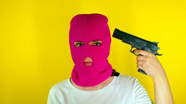 Sarı arka planda silahlı, pembe kar maskeli, tanınmayan bir kadını yakından çek. Maskeli kimliği belirsiz bir kadın kafasına silah doğrultuyor, taklit atışı. Kafadaki düşünce patlaması kavramı