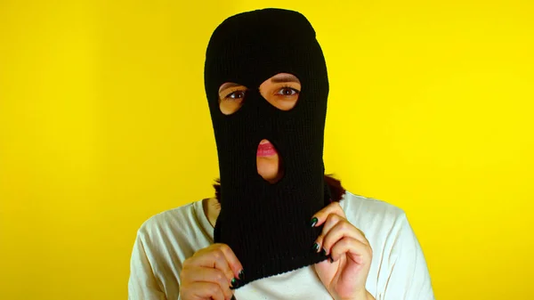 Close Young Woman Puts Black Balaclava Yellow Background Secretive Female — Stock Photo, Image