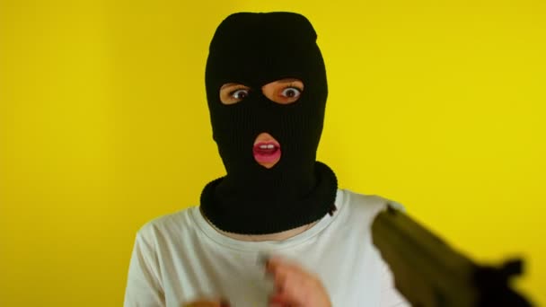 Onherkenbaar Persoon Richt Pistool Gevaarlijke Crimineel Zwarte Bivakmuts Gele Achtergrond — Stockvideo