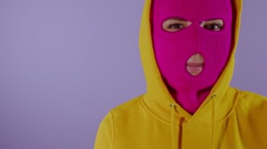 Mor arka planda pembe kar maskeli, tanınmayan bir kadını yakından çek. Maskeli kadın flört ediyor ve kameraya bakıyor..