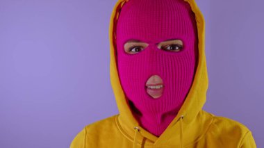 Pembe kar maskeli tanınmayan bir kadın mor arka planda gülümsüyor. Maskeli bilinmeyen bir kadın gülümsüyor ve kameraya bakıyor.