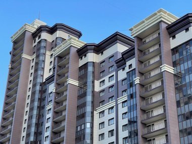 Mavi gökyüzü olan güneşli bir günde modern bir apartman. Modern bir apartmanın ön cephesi. Modern apartman binası mimarisi.