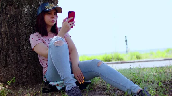 Mujer Joven Descansa Con Teléfono Móvil Sentado Cerca Del Árbol — Foto de Stock